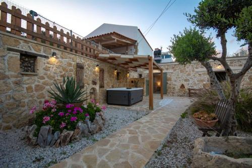 a courtyard of a stone house with flowers at Pamelas House with Jacuzzi in Kissamos