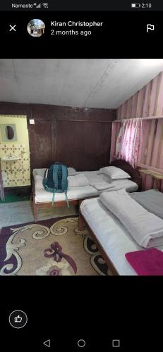 a room with three beds and a backpack on a rug at Jungle Crown Organic Homestay in Nagarkot