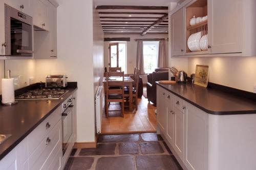 a kitchen with white cabinets and a dining room at No 3 The Forge Coniston in Coniston