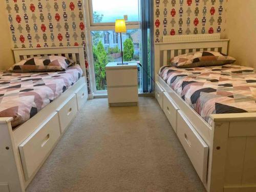 a bedroom with two beds and a window at Cosy House near city centre and football stadium in Manchester