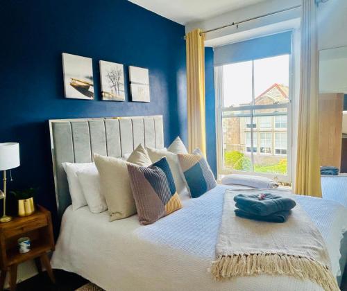 Un dormitorio con una cama con paredes azules y una ventana en Lovely 1-bedroom serviced apartment in Falmouth, en Falmouth