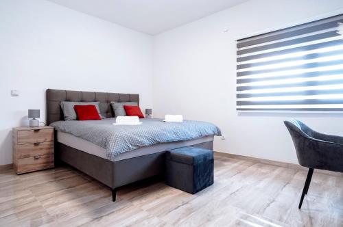 a bedroom with a bed with red pillows and a chair at Apartman Ružić in Sveti Ivan Žabno