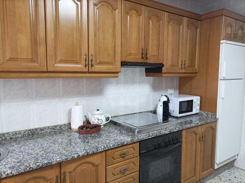 a kitchen with wooden cabinets and a white microwave at Dona Branca in Quiroga
