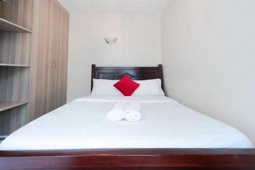 a bedroom with a bed with a red pillow at The Bliss - Lovely 1 bedroom apartment located near TRM mall in Nairobi