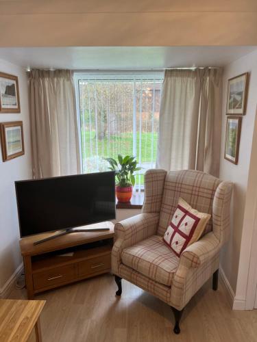 sala de estar con silla y TV de pantalla plana en Luxury Super King Bed, en Stratford-upon-Avon