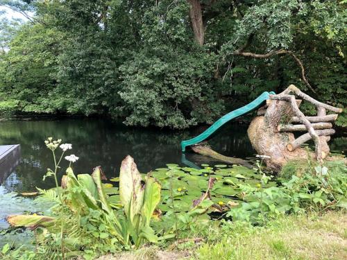 a garden with a pond with a wooden fence at The Barn House - Swimming Pond,Jacuzzi,Chicks! in Battle