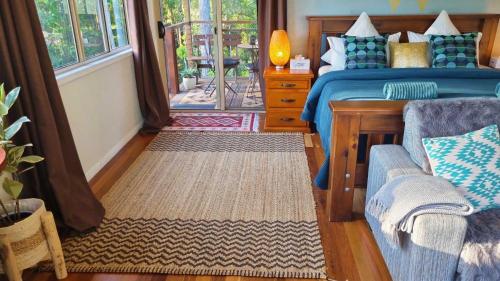 1 dormitorio con cama, sofá y ventana en Deluxe Studio with Forest Views, Noosa Hinterland, en Doonan