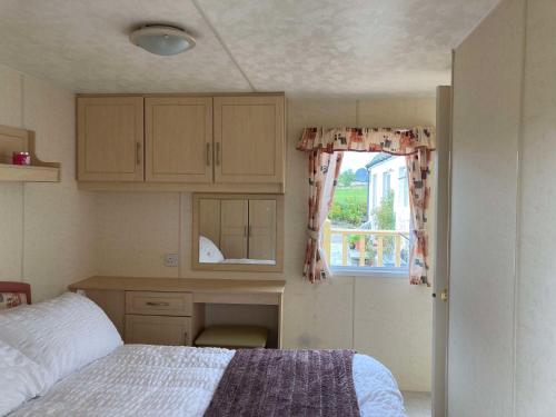 a bedroom with a bed and a desk and a window at Clashmore Wood in Dornoch