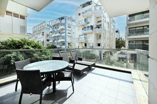 Cet appartement dispose d'une terrasse avec une table et des chaises sur un balcon. dans l'établissement Mamma Mia by HolyGuest, à Tel Aviv