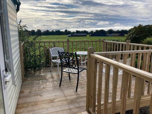 a patio with two chairs and a table on a deck at Clashmore Wood in Dornoch