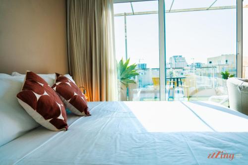 sypialnia z łóżkiem z poduszkami i dużym oknem w obiekcie Gorgeous seaviews from a stunning studio w mieście Sliema