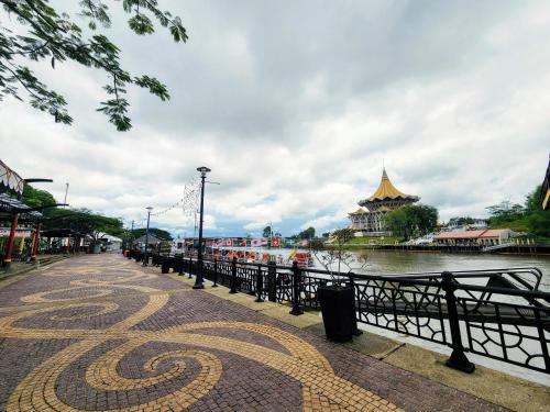 una passerella accanto a un corpo idrico con un edificio di Upspot Kuching Waterfront Premium Hostel a Kuching