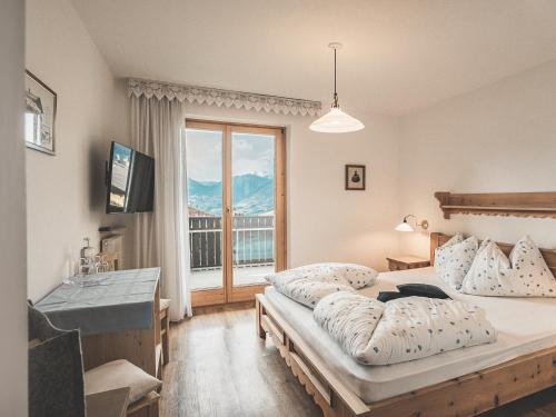 a bedroom with two beds and a large window at Hotel Turmwies in Tirolo