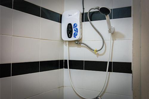 y baño con ducha y secador de pelo en la pared. en Upspot Kuching Waterfront Premium Hostel en Kuching