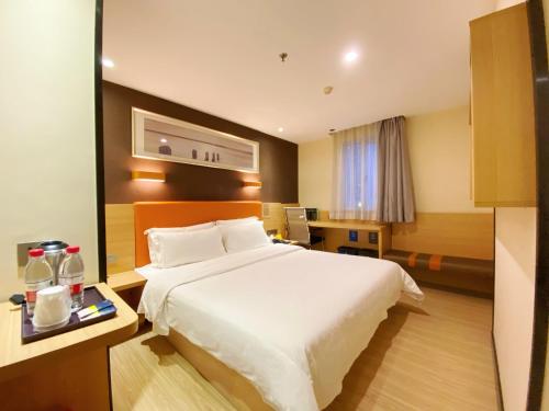 a hotel room with a white bed and a desk at 7Days Premium Guangzhou Chenjiaci Dukang Avenue in Guangzhou
