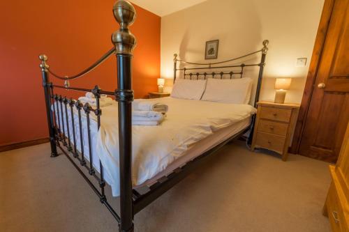 a bed in a bedroom with an orange wall at Poppy Cottage, lake view holiday cottage in Coniston in Coniston