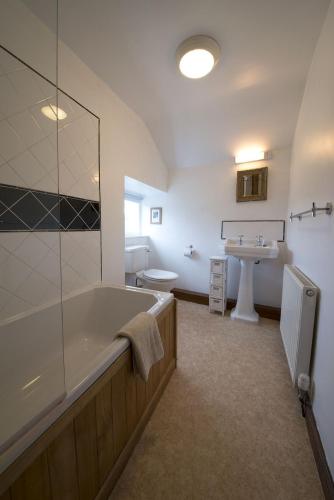 a bathroom with a tub and a toilet and a sink at Poppy Cottage, lake view holiday cottage in Coniston in Coniston