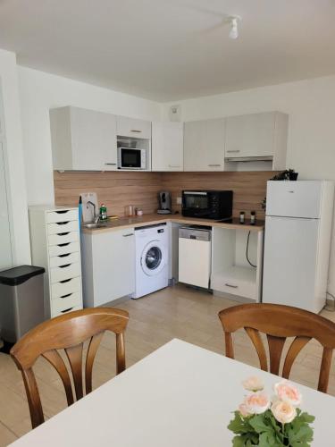 une cuisine avec des armoires blanches et une table et des chaises dans l'établissement Superbes appartements neufs à Montpellier, à Montpellier