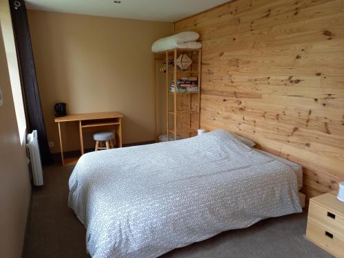 ein Schlafzimmer mit einem weißen Bett und einer Holzwand in der Unterkunft La fermette - chambres d'hôtes dans environnement calme et arboré in Saint-Jean-des-Baisants