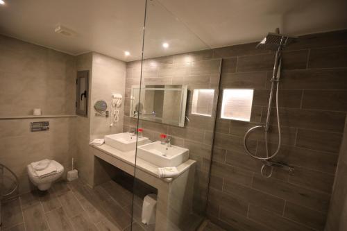 a bathroom with a shower and a sink and a toilet at Suites Hôtel Les Charmilles & Spa in La Marsa