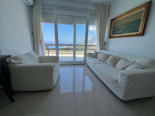 a living room with two white couches and a large window at The Olives Terrace Residences in Dhërmi