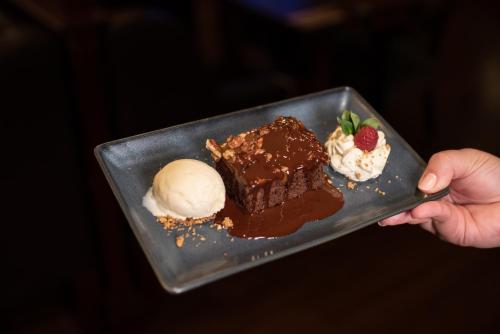 a person holding a plate with chocolate cake and ice cream at Errigal Country House Hotel in Cootehill
