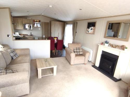 ein Wohnzimmer mit einem Sofa und einem Kamin in der Unterkunft Sand Le Mere Holiday Village Caravan hire in Tunstall