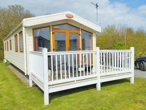 a tiny house with a porch and a white fence at Sand Le Mere Holiday Village Caravan hire in Tunstall