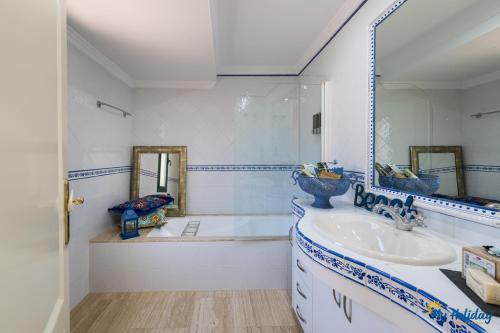 een badkamer met een bad, een wastafel en een spiegel bij Villa Monte Leon in Maspalomas