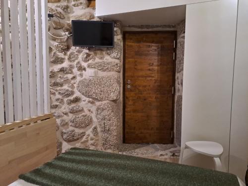 a bedroom with a stone wall with a television on the wall at VillaGarcia-Casa da Marianinha in Terras de Bouro