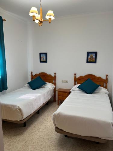 2 camas en una habitación con paredes blancas y almohadas azules en VILLA LA MOMITA, en Chiclana de la Frontera
