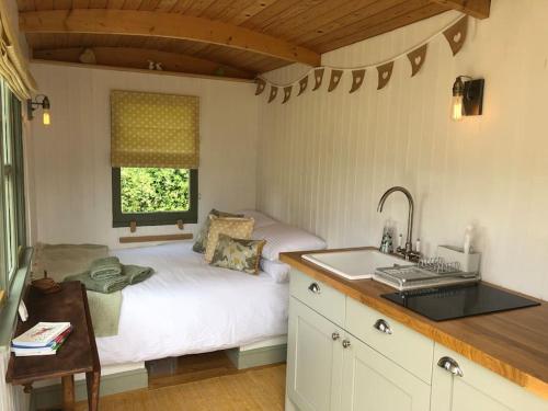 a kitchen with a bed and a sink in a room at The Warren - Cosy Shepherds Hut in beautiful wild meadow in Halesworth