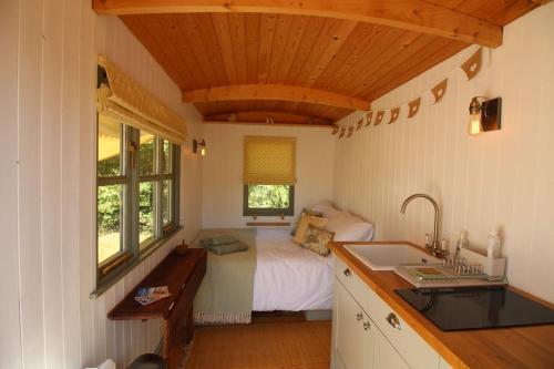 a bedroom with a bed and a sink in a room at The Warren - Cosy Shepherds Hut in beautiful wild meadow in Halesworth