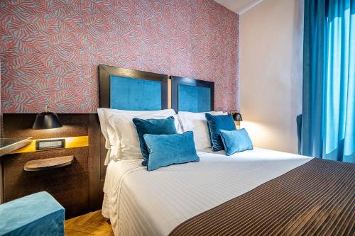 a bedroom with a large bed with blue pillows at Hotel Duomo Firenze in Florence