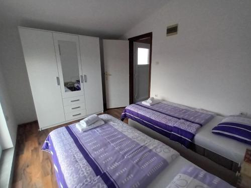 een slaapkamer met 2 bedden, een kast en een spiegel bij Apartman Štrkalj in Tisno