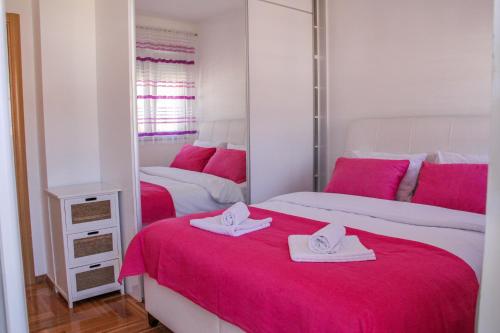 a bedroom with two beds with pink sheets and a mirror at Lanai Apartment in Trebinje