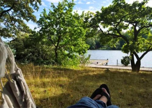 a person laying in a hammock near a lake at Escape to Your Very Own Private Island - Just 30 Minutes from Stockholm in Svartsjö