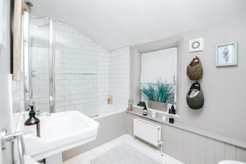 Soho House - 4 Bedrooms, Central Henley في هينلي على نهر التايمز: حمام أبيض مع حوض وحوض استحمام