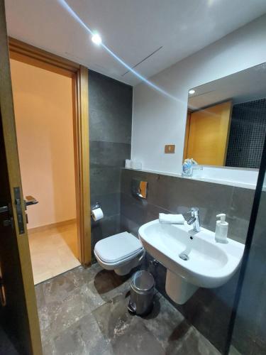 a bathroom with a sink and a toilet and a mirror at Nayah Stays, Beautiful 3-bedroom vacation home with lovely pool in Hurghada