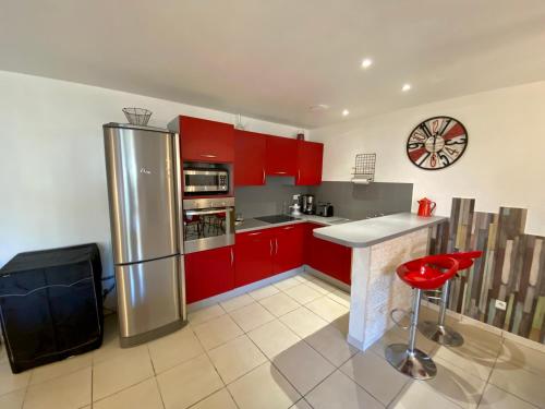 La cuisine est équipée de placards rouges et d'un réfrigérateur en acier inoxydable. dans l'établissement Gîte Romarin avec SPA, à Saint-Jean-de-Barrou