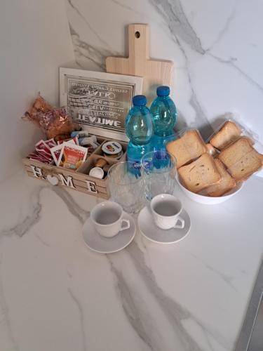 a table with two cups and a tray of bread and bottles at M. Szwed. Guest House old Bari in Bari