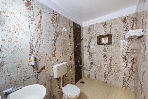 a bathroom with a toilet and a wall covered in paint at Yorkshire Inn in Mount Ābu