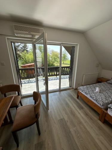1 dormitorio con cama, mesa y balcón en Hangulatos Balaton parti nyaraló, en Révfülöp