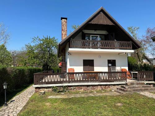 a large white house with a balcony on top at Hangulatos Balaton parti nyaraló in Révfülöp
