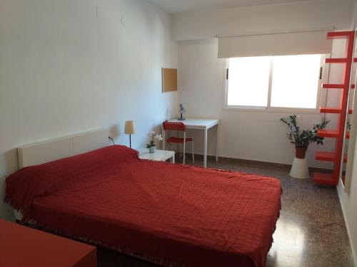 1 dormitorio con cama roja y escritorio en PISO EN BURJASOT en Burjasot