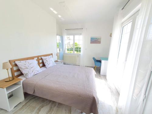 una camera bianca con un grande letto e finestre di Logement entier avec grand jardin et parking WIFI 6 et Fibre a Berck-sur-Mer