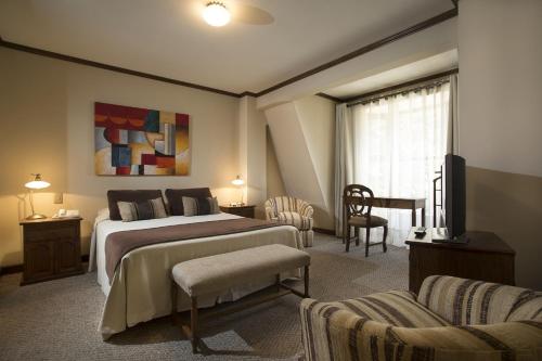 Hotel Tierra Del Fuego في بونتا أريناس: غرفة نوم بسرير ومكتب وتلفزيون