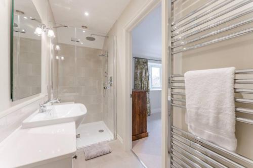 y baño blanco con lavabo y ducha. en Miller Retreat Stunning thatched cottage with garden and parking, en Weybourne