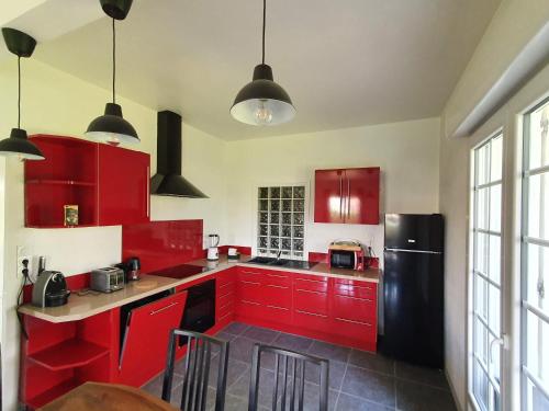 una cucina con armadi rossi e frigorifero nero di Logement entier avec grand jardin et parking WIFI 6 et Fibre a Berck-sur-Mer