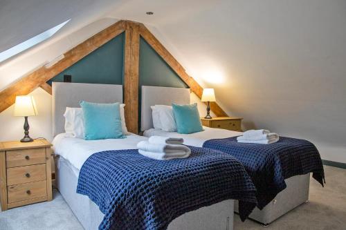 WirksworthにあるStainsborough Hall Holiday Cottagesのベッドルーム1室(青と白のシーツが備わるベッド2台付)